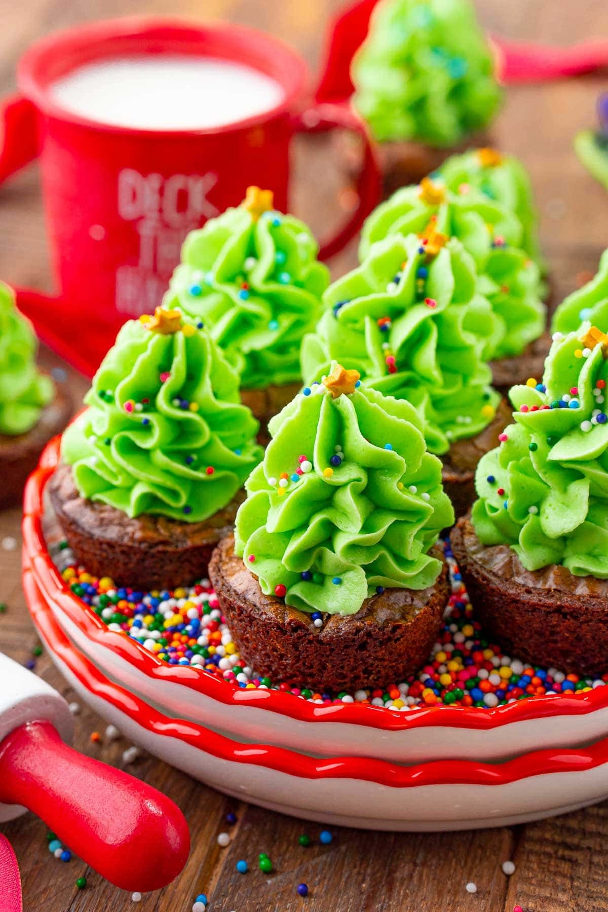 Mini brownie cupcakes placed on a bed of sprinkles with green icing piping on top.