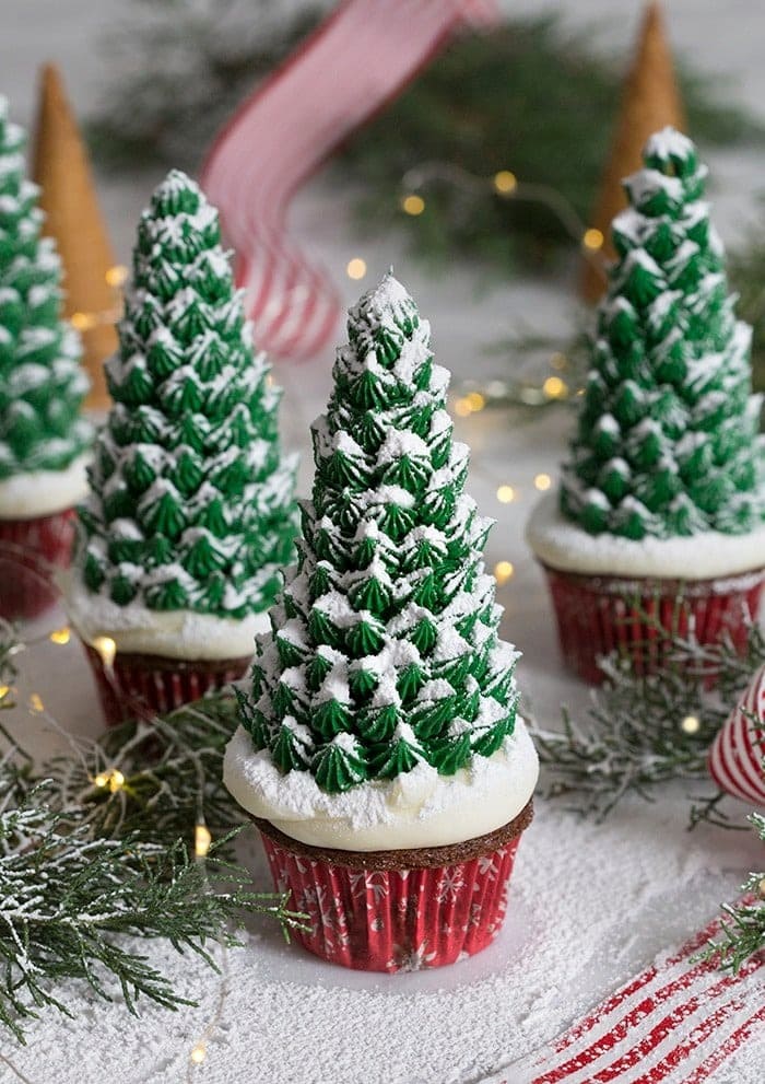 Cupcakes topped with icing shaped in Christmas tree dusted with powdered sugar. 