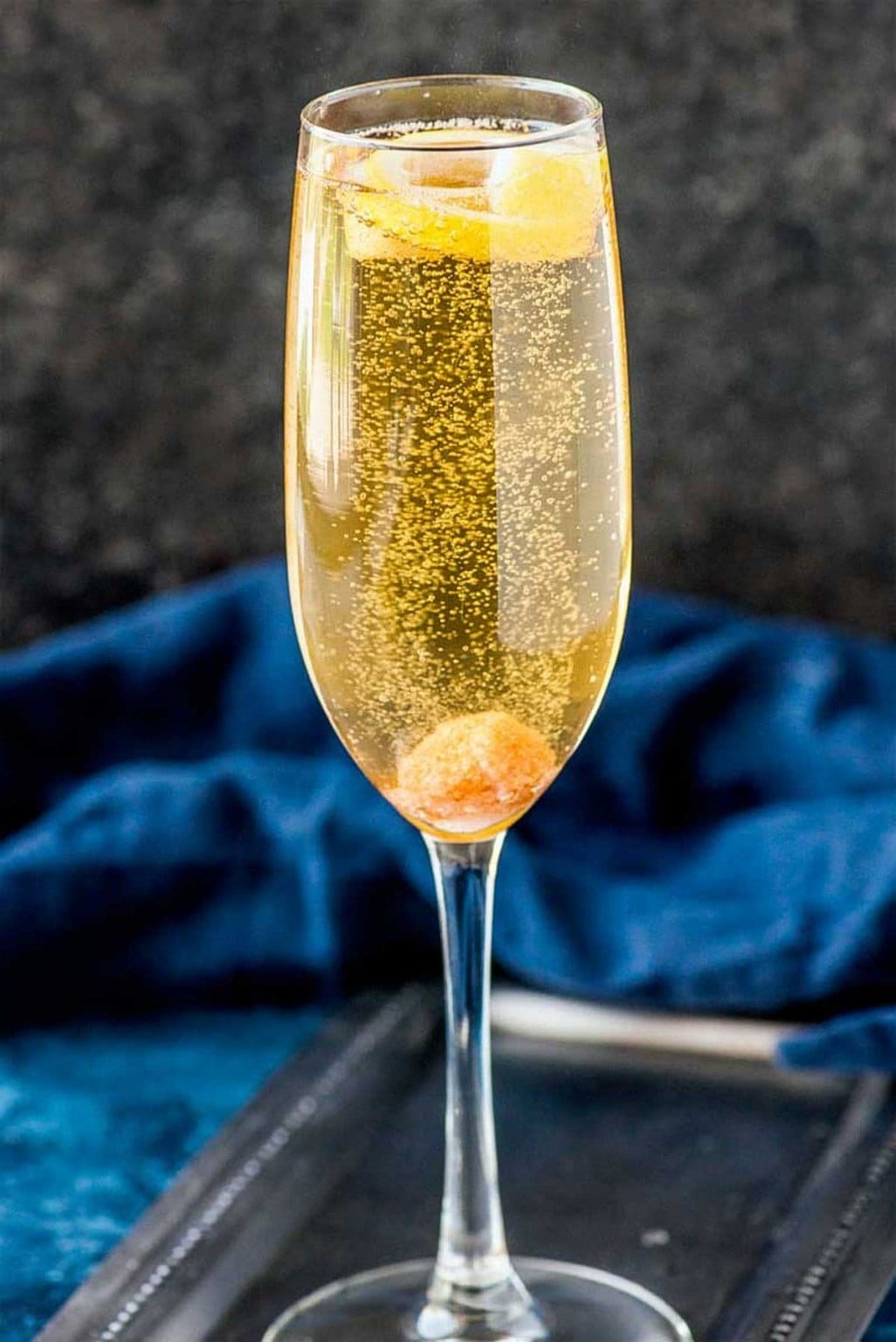A glass of sparkling champagne garnished with lemon slices. 