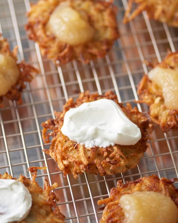 Potato pancakes topped with sour cream on a cooling rack.