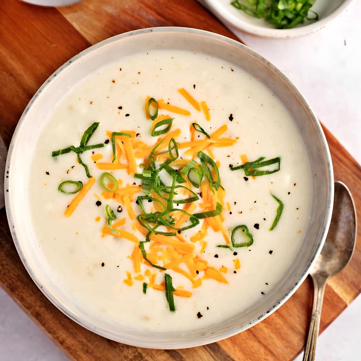 Closeup of potato soup served on a bowl topped with grated cheese. 