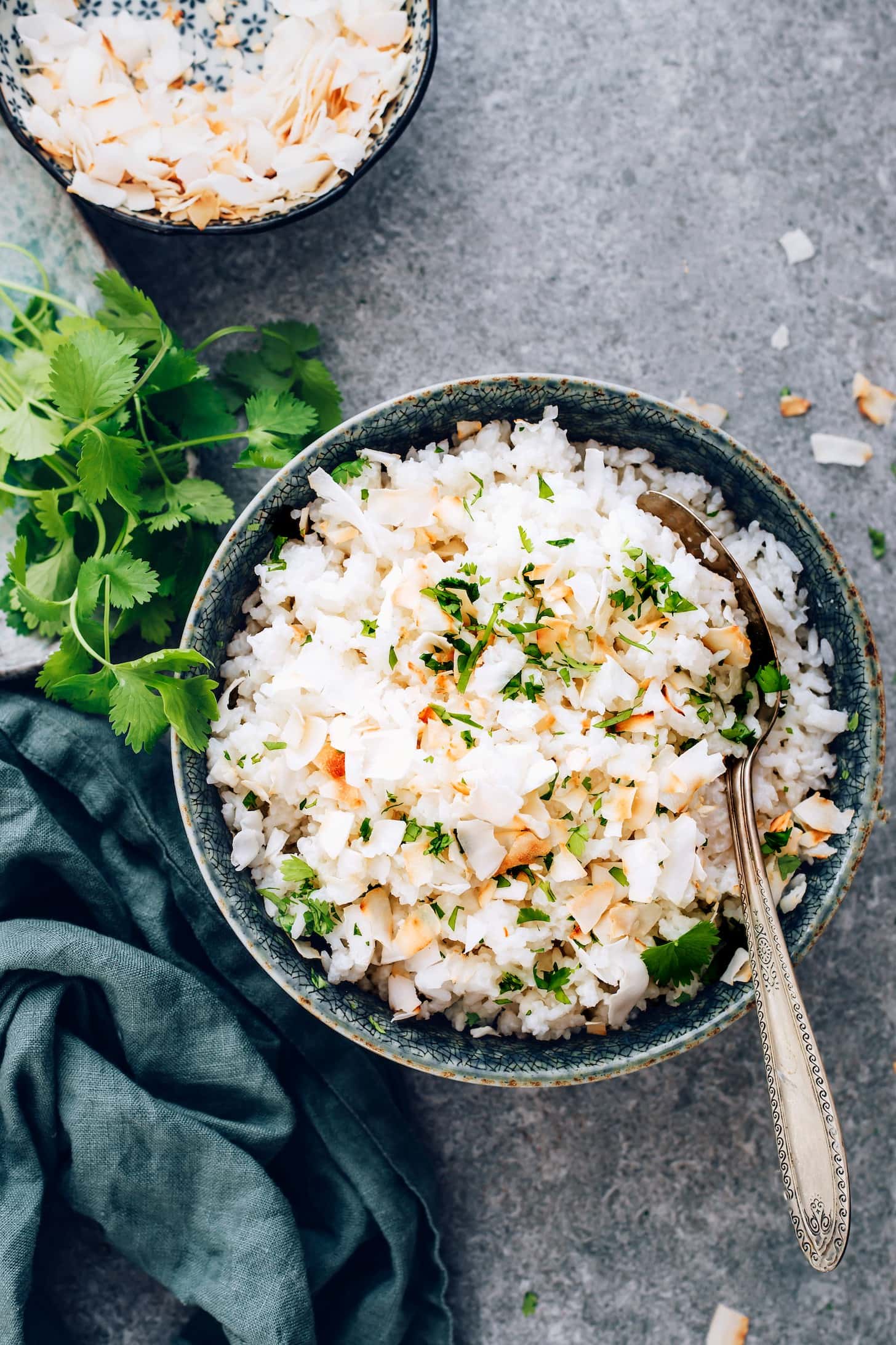 Rice topped with  flaky filet and side of coconut rice garnished with chopped parsley leaves. 