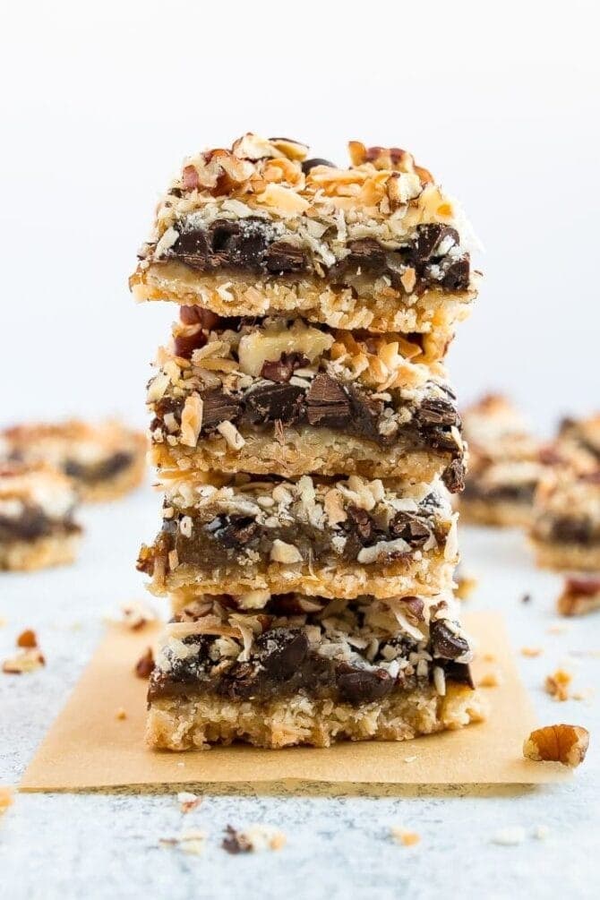 A stack of cookie bars with grains, graham cracker crust, chopped chocolate and nuts. 