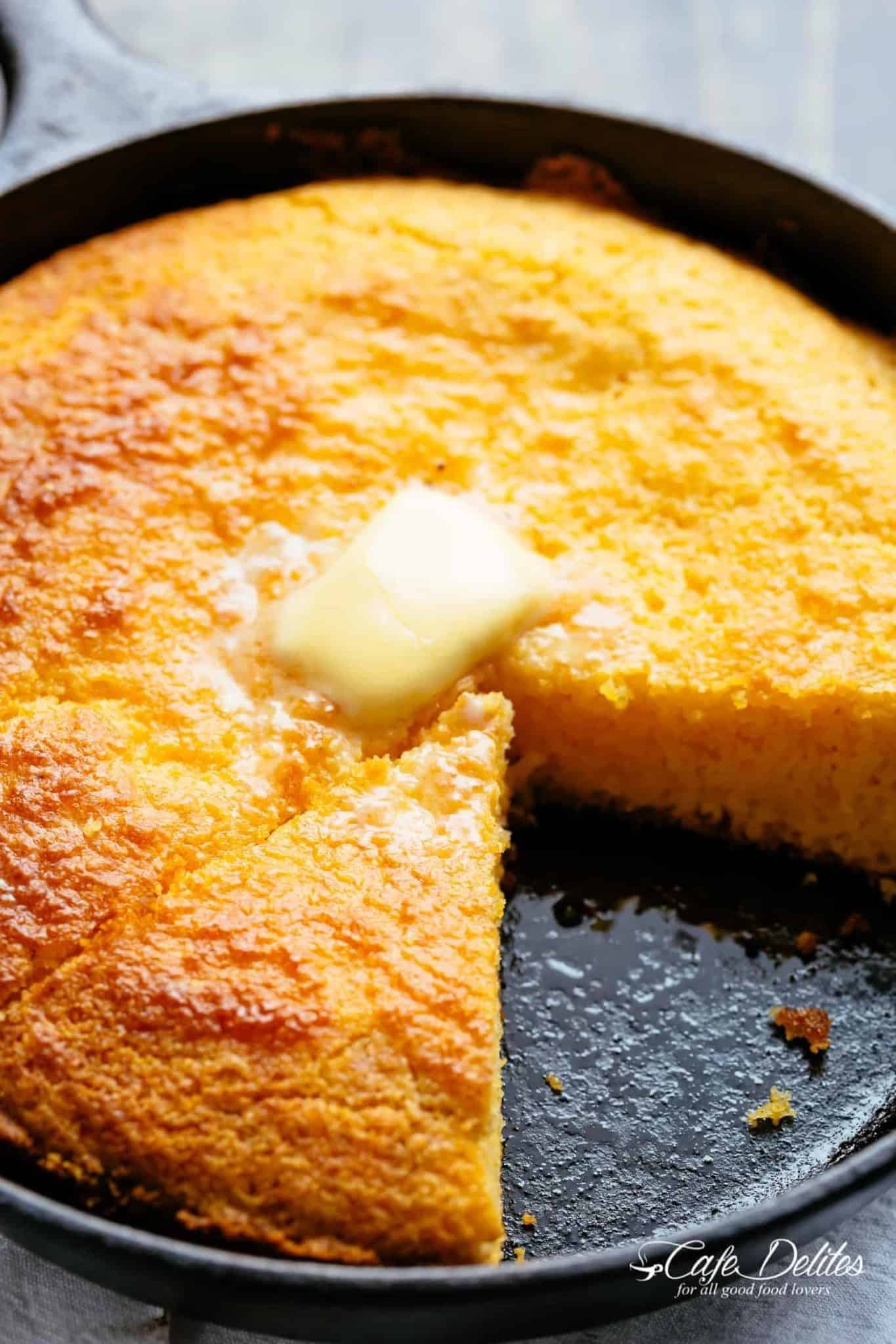 Cornbread with a portion missing cooked in a cast iron skillet. 