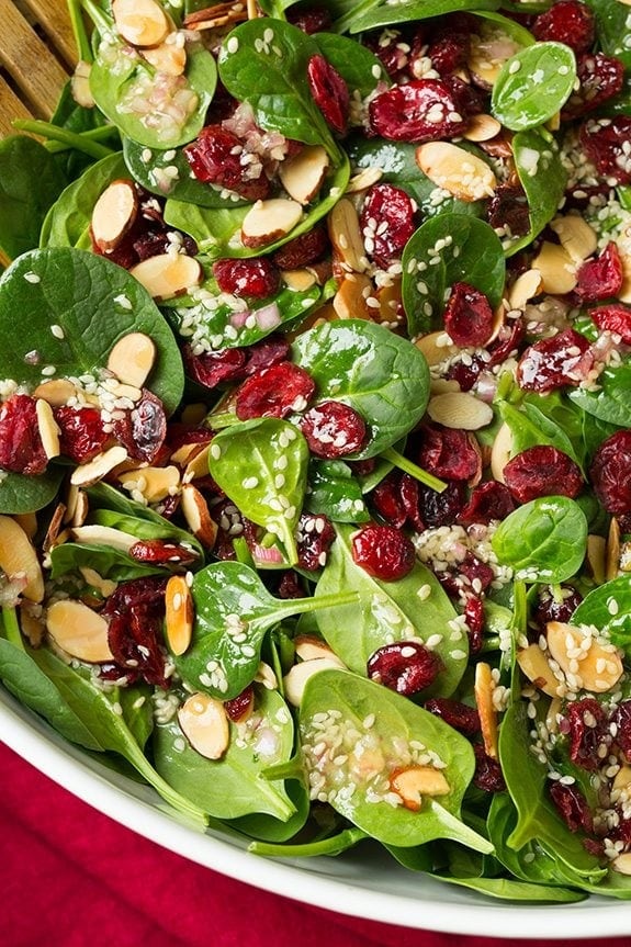 Salad with dried cranberries, nuts, basil leaves and dressing. 