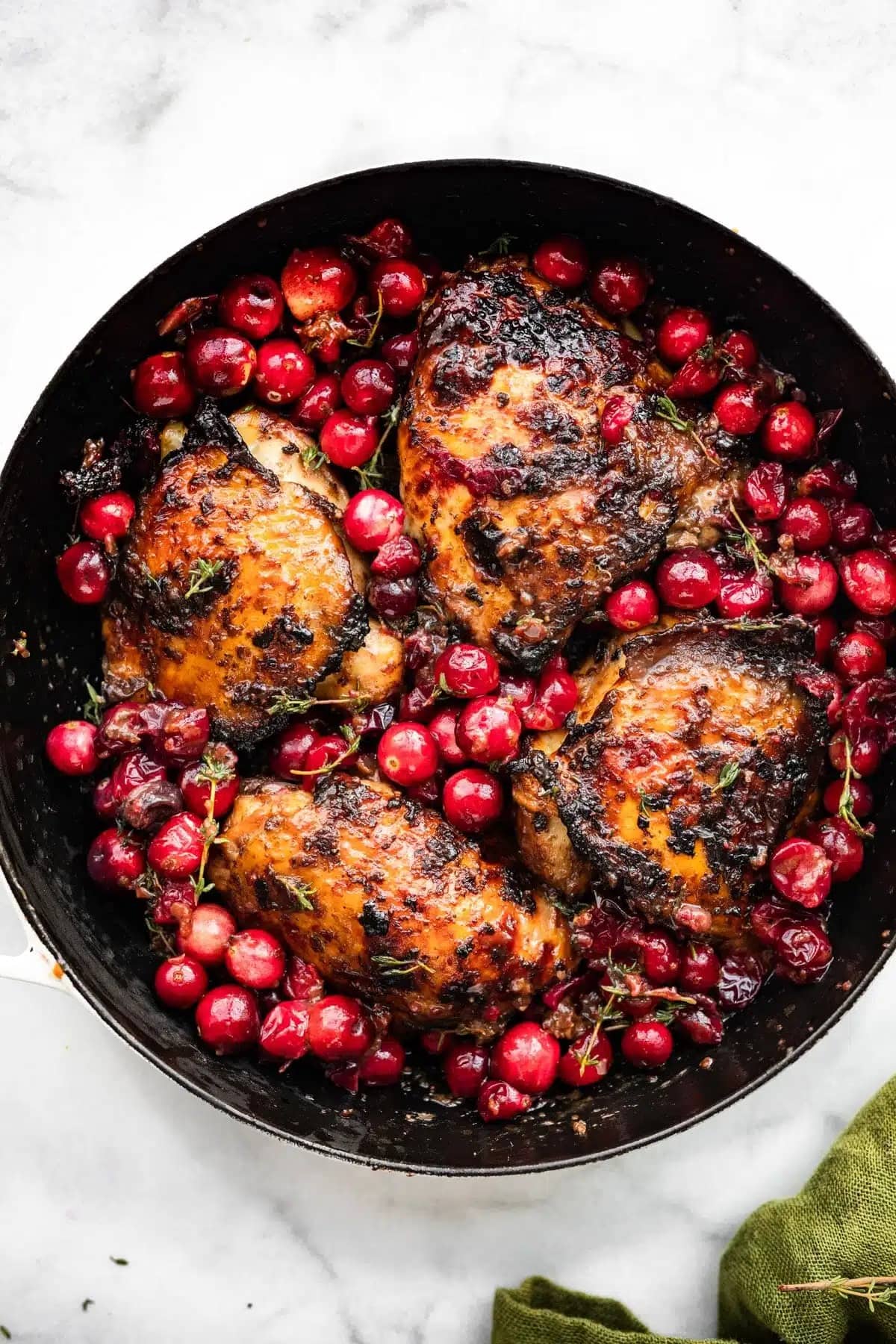Roasted chicken with cranberry and herbs cooked on a skillet.