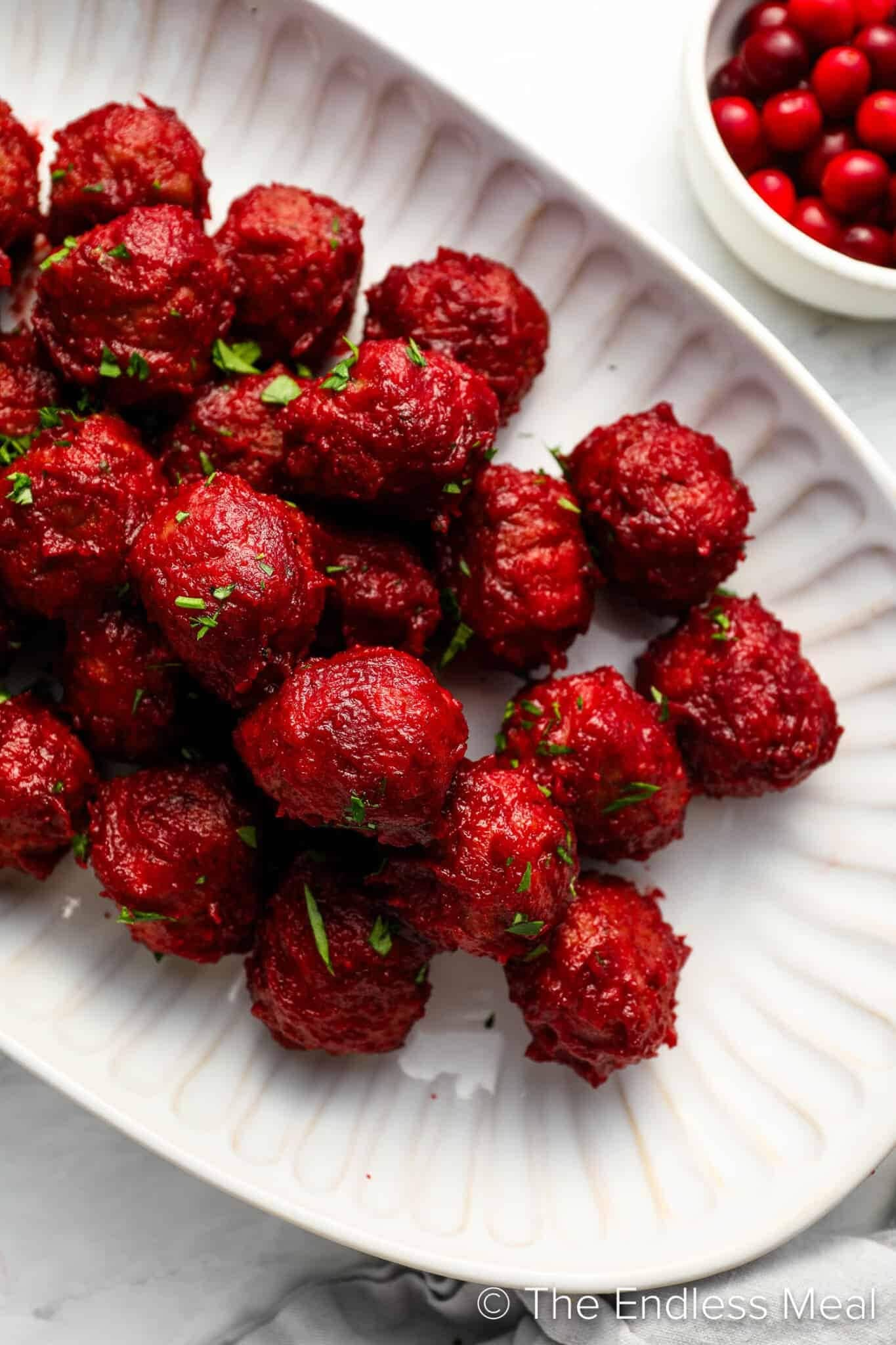 Bunch of bright red color meatballs on white plate.
