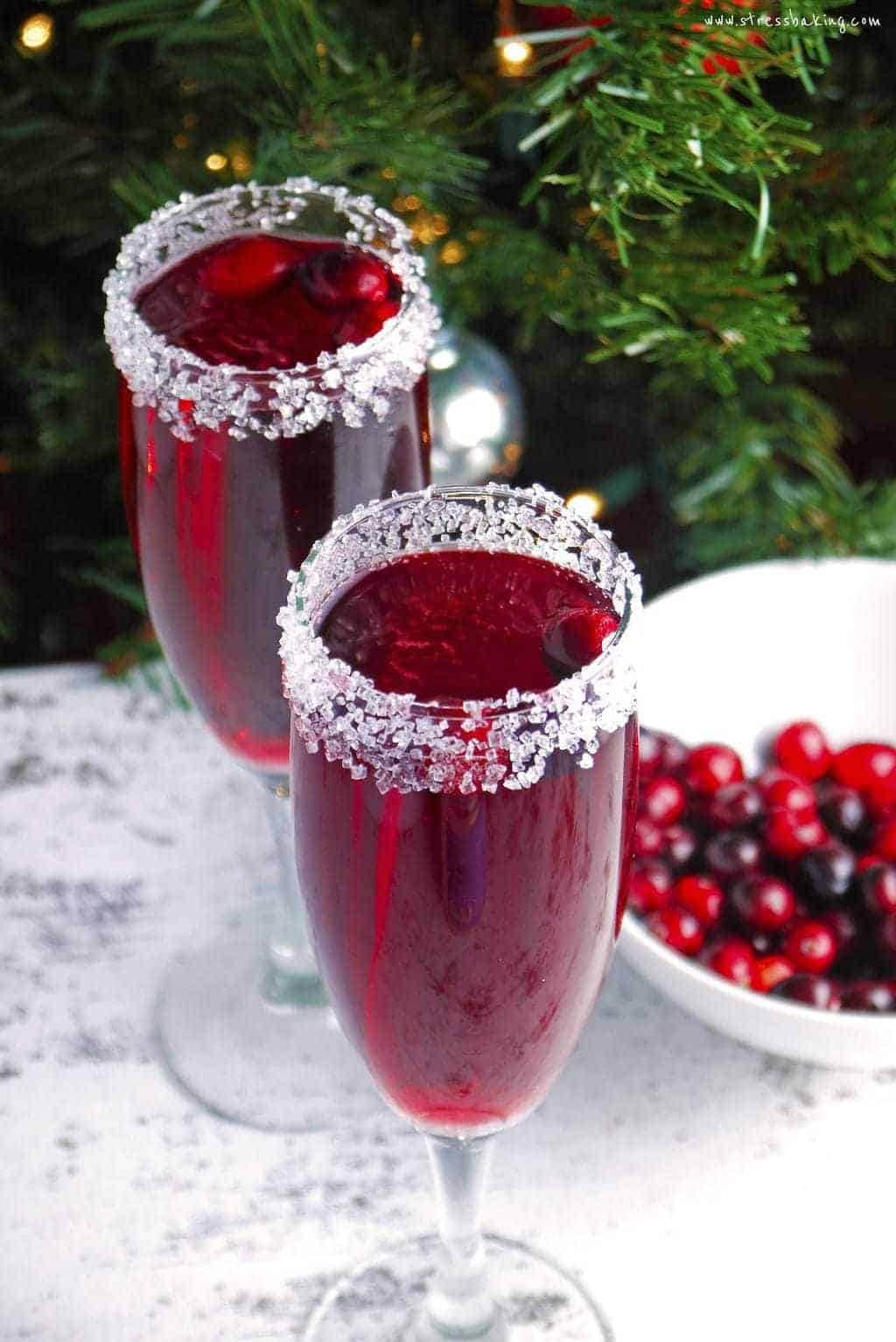 Two glasses of cranberry punch with a bowl of cranberries.