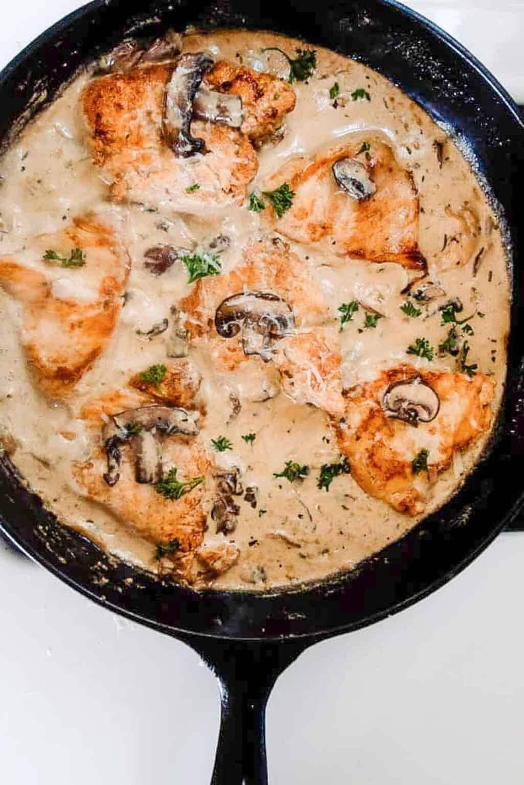 A skillet with chicken and mushrooms in a creamy sauce
