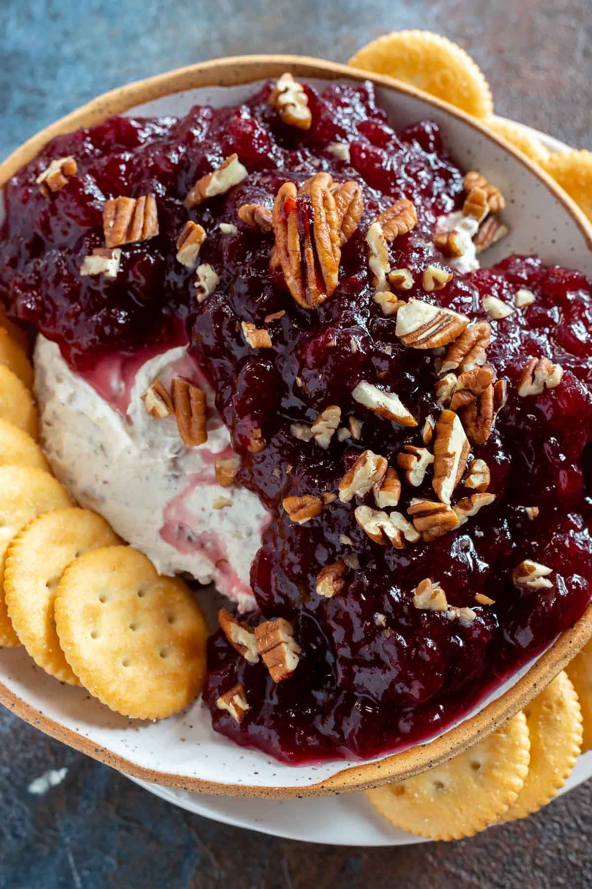 Creamy cranberry dip topped with crushed pecan nuts served with crackers.