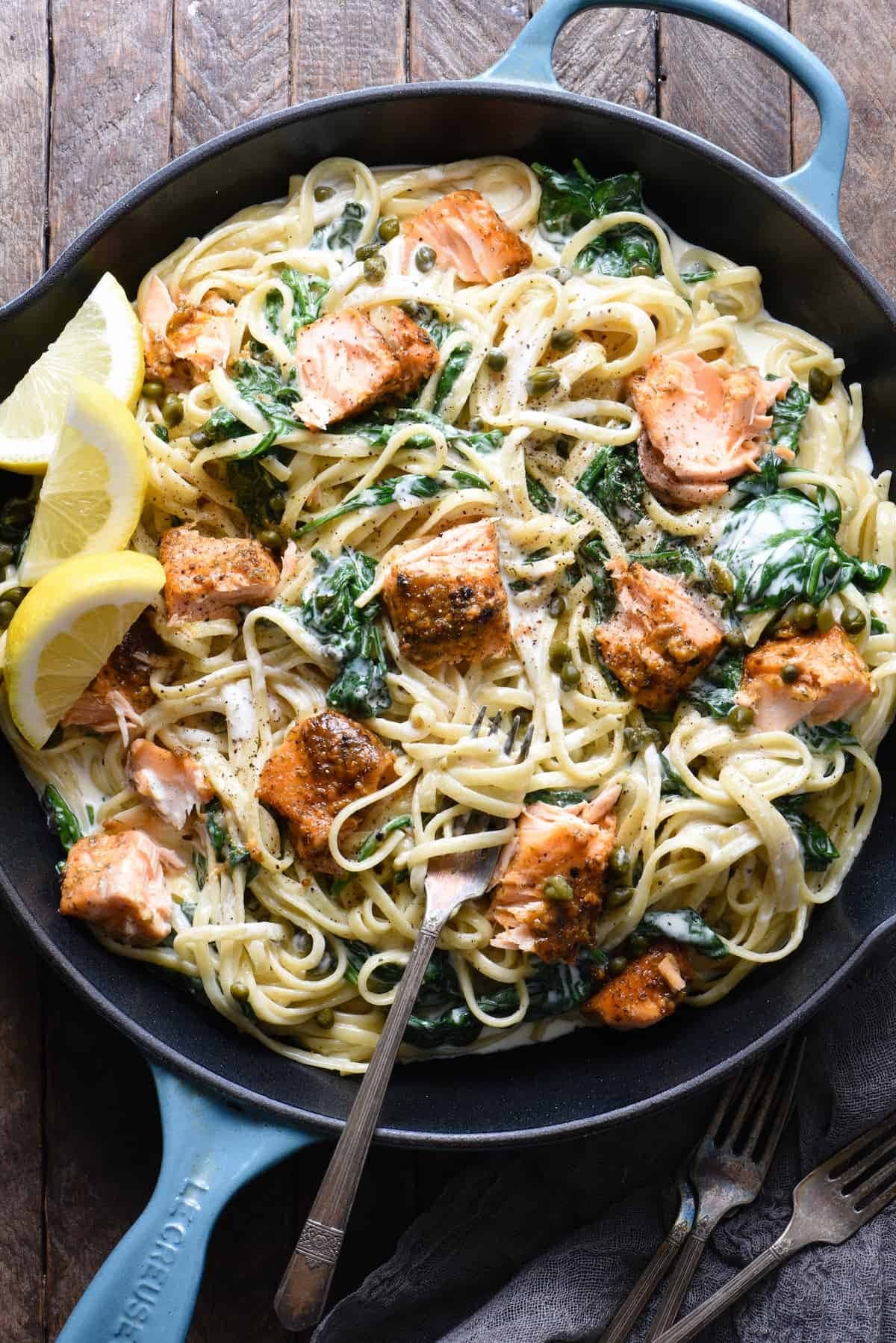 Pasta on skillet made with linguine, spinach, and salmon filets.