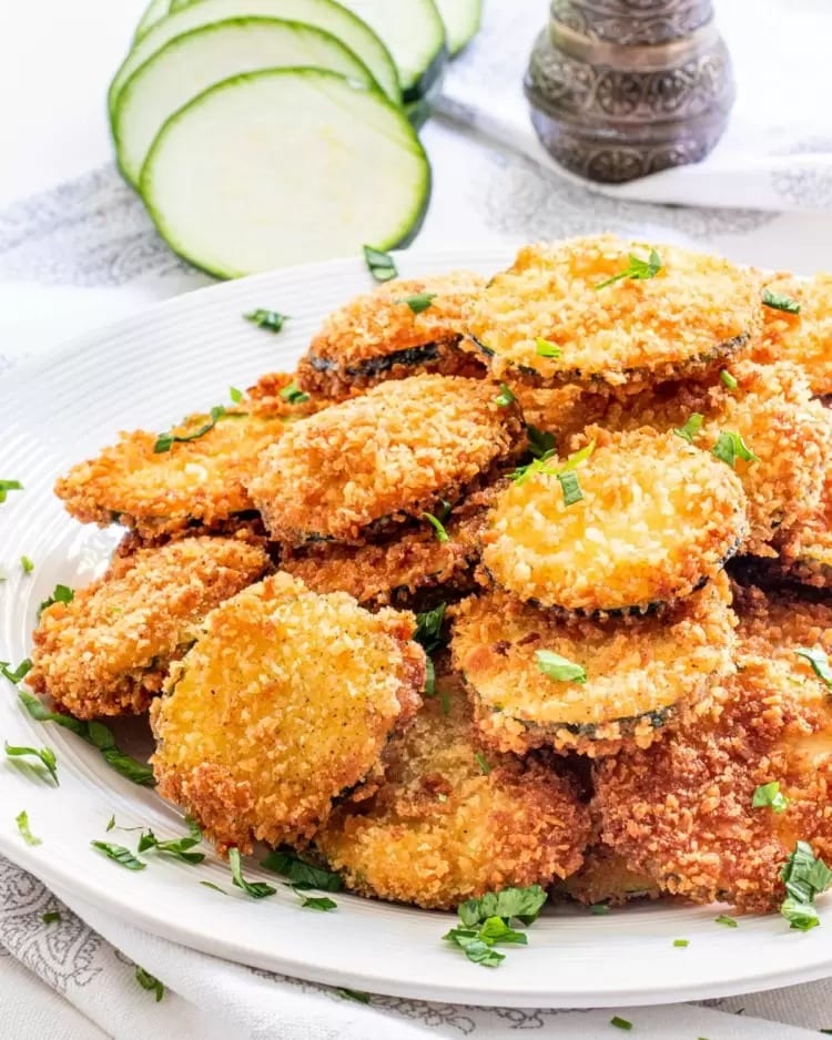 Bunch of fried breaded zucchini served on a plate. 
