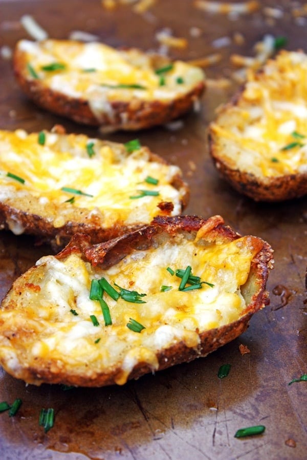 Potato skin topped with melting cheese and chopped onion leaves.