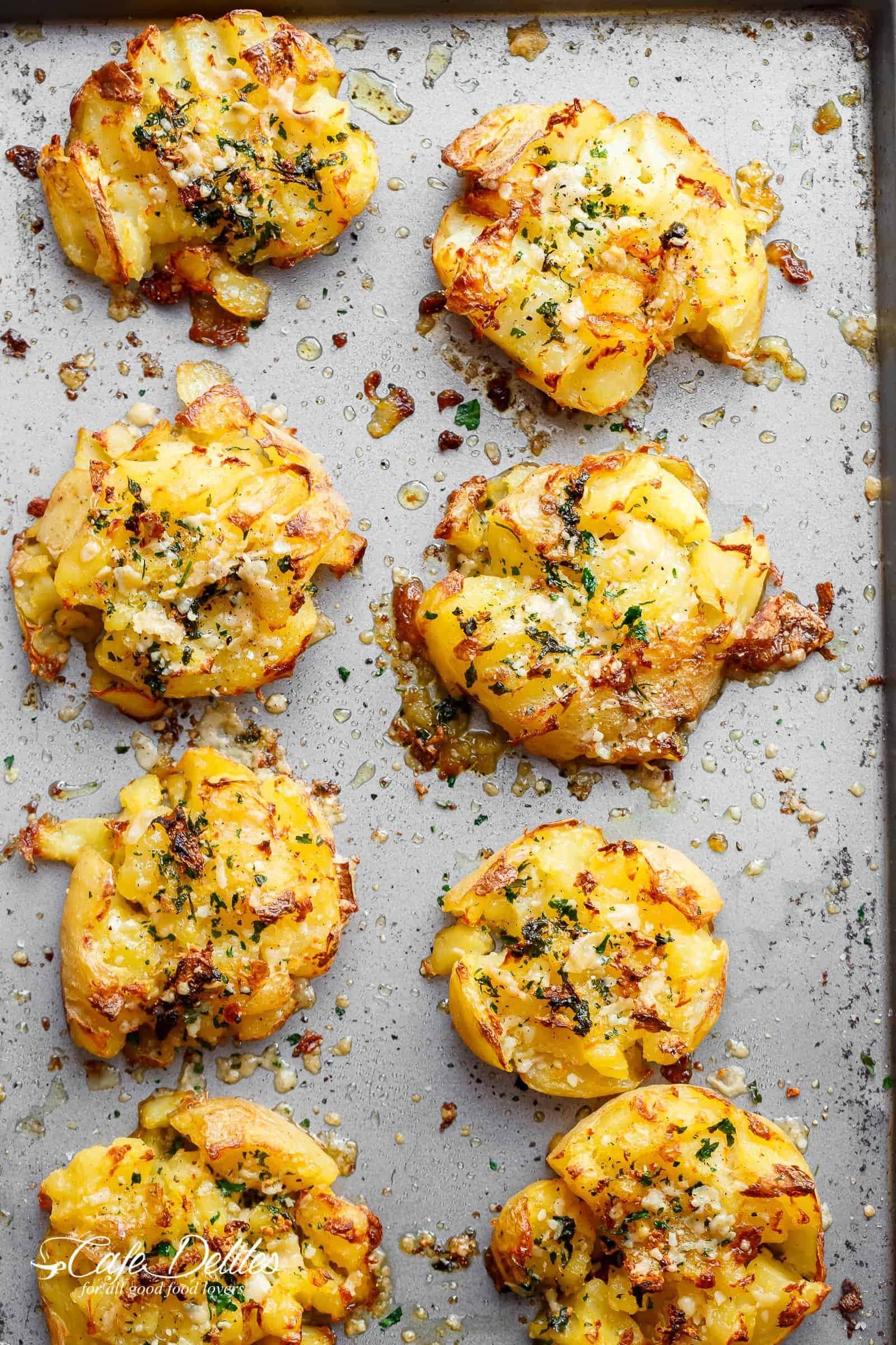 Crispy smashed potatoes on sheet pan with herbs and cheese. 