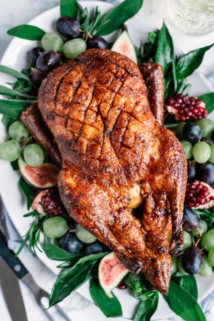 Whole glazed roast duck served on a bed of herbs and berries. 