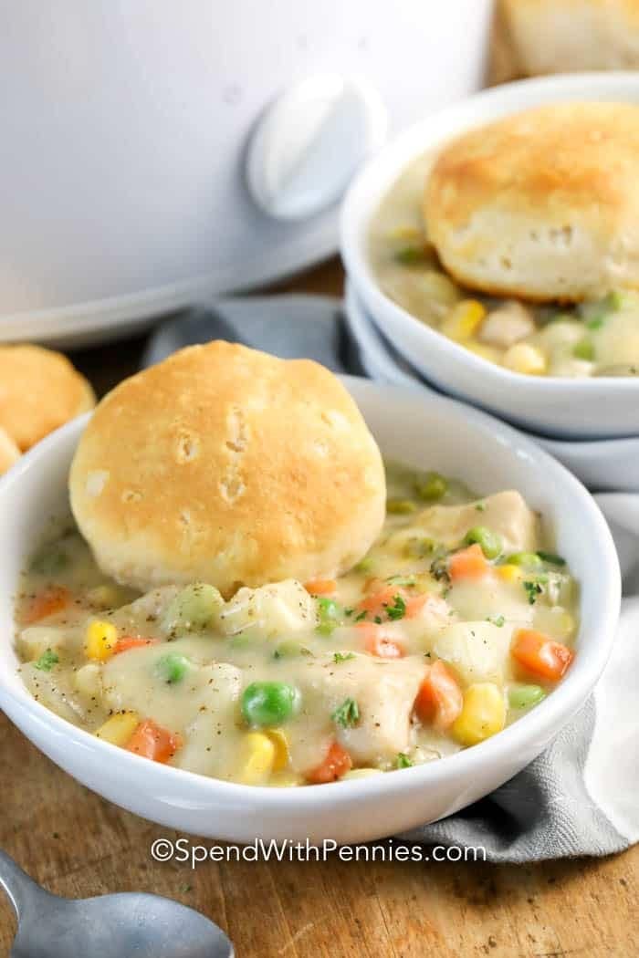 A serving of chicken pot pie filling with a piece of biscuits in a bowl.