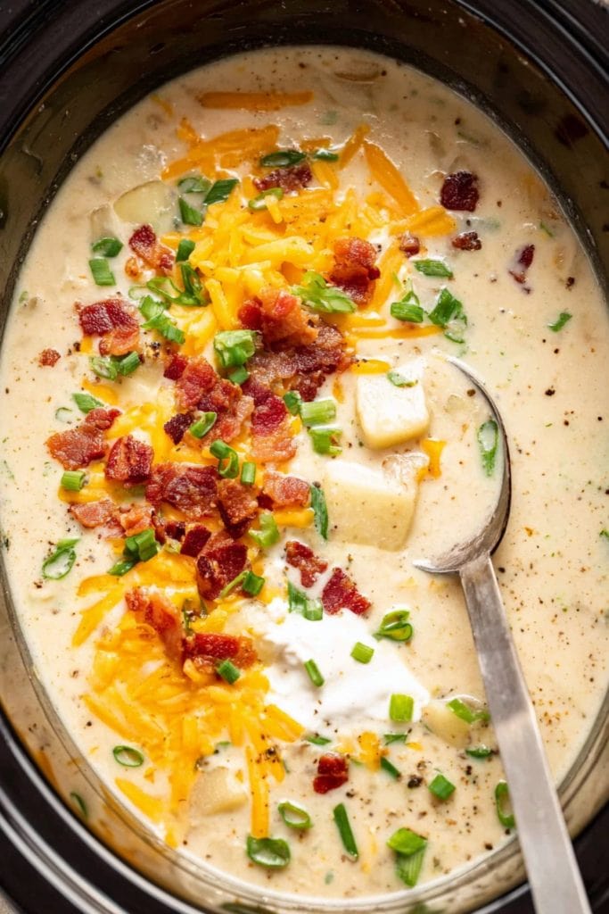 An overhead view of potato soup with bacon bits, cheese and green onions.