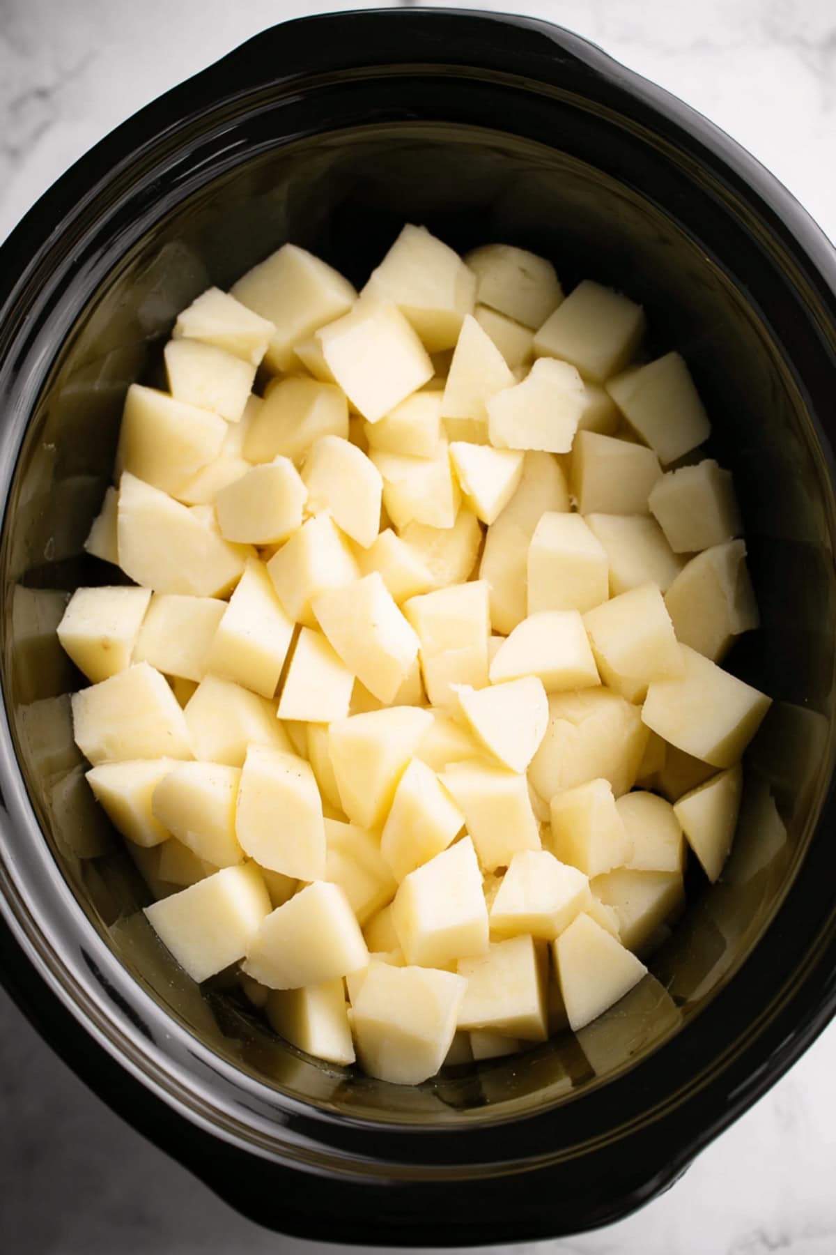 Chopped potatoes in a black slow cooker