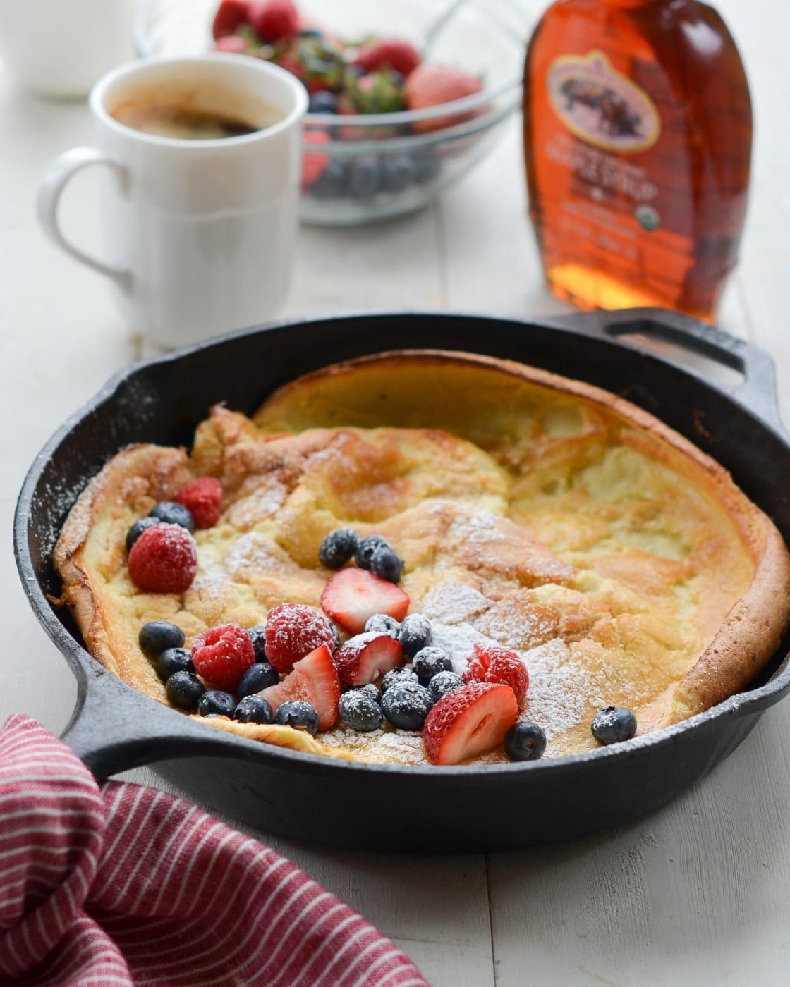 Puffy pancake baked in a sizzling-hot buttered skillet with fresh blueberries, raspberries and strawberries on top