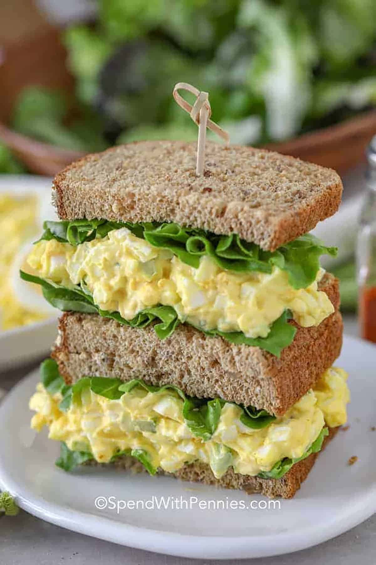Sliced in half wheat bread sandwich with egg salad and lettuce filling.