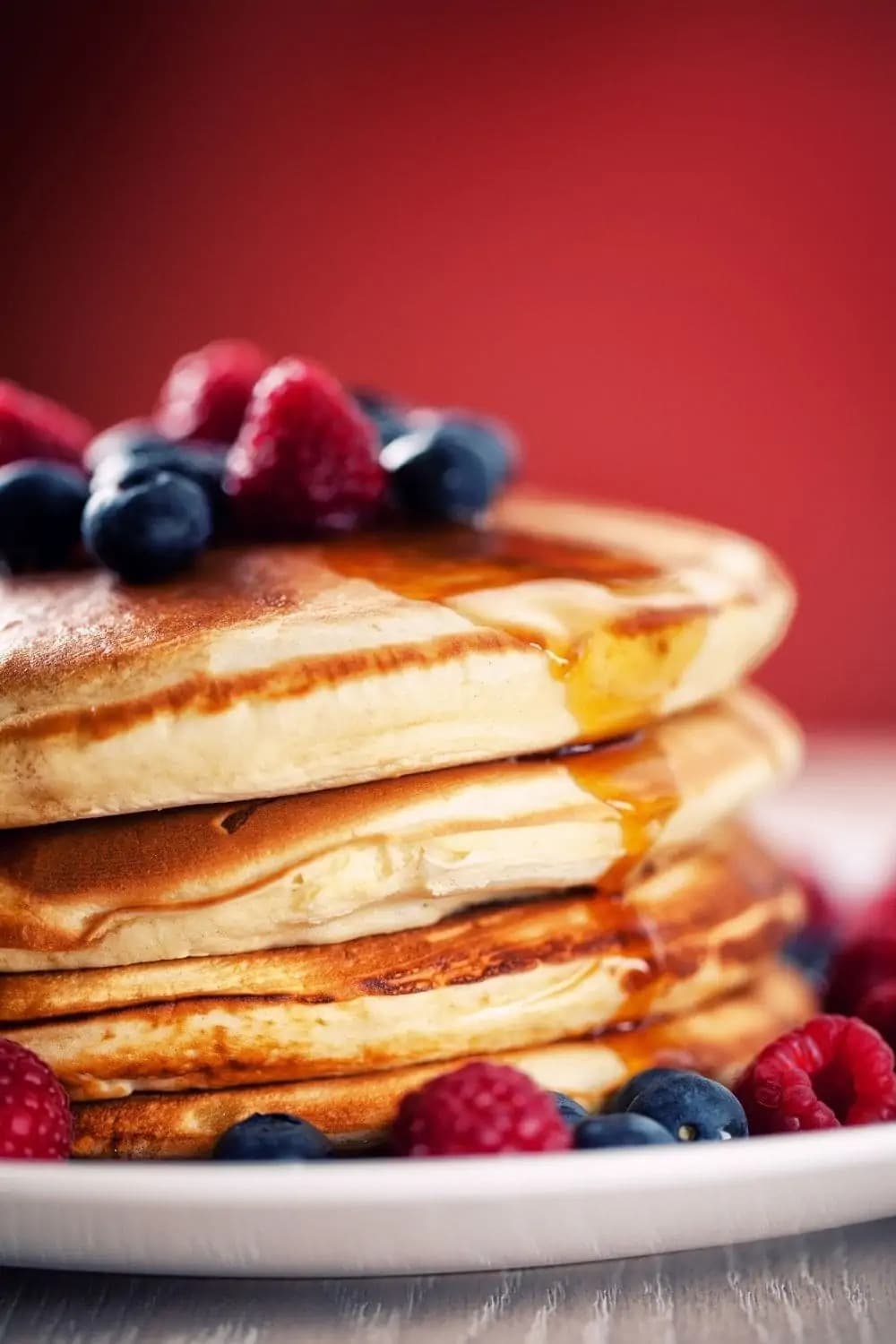 A stack of pancakes topped with fresh berries and maple syrup. 