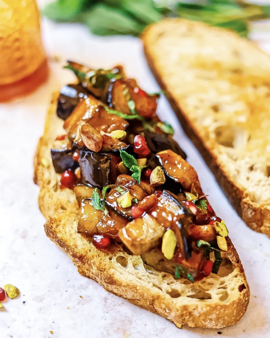 Sliced crostini topped with eggplant salad with pomegranate seeds,