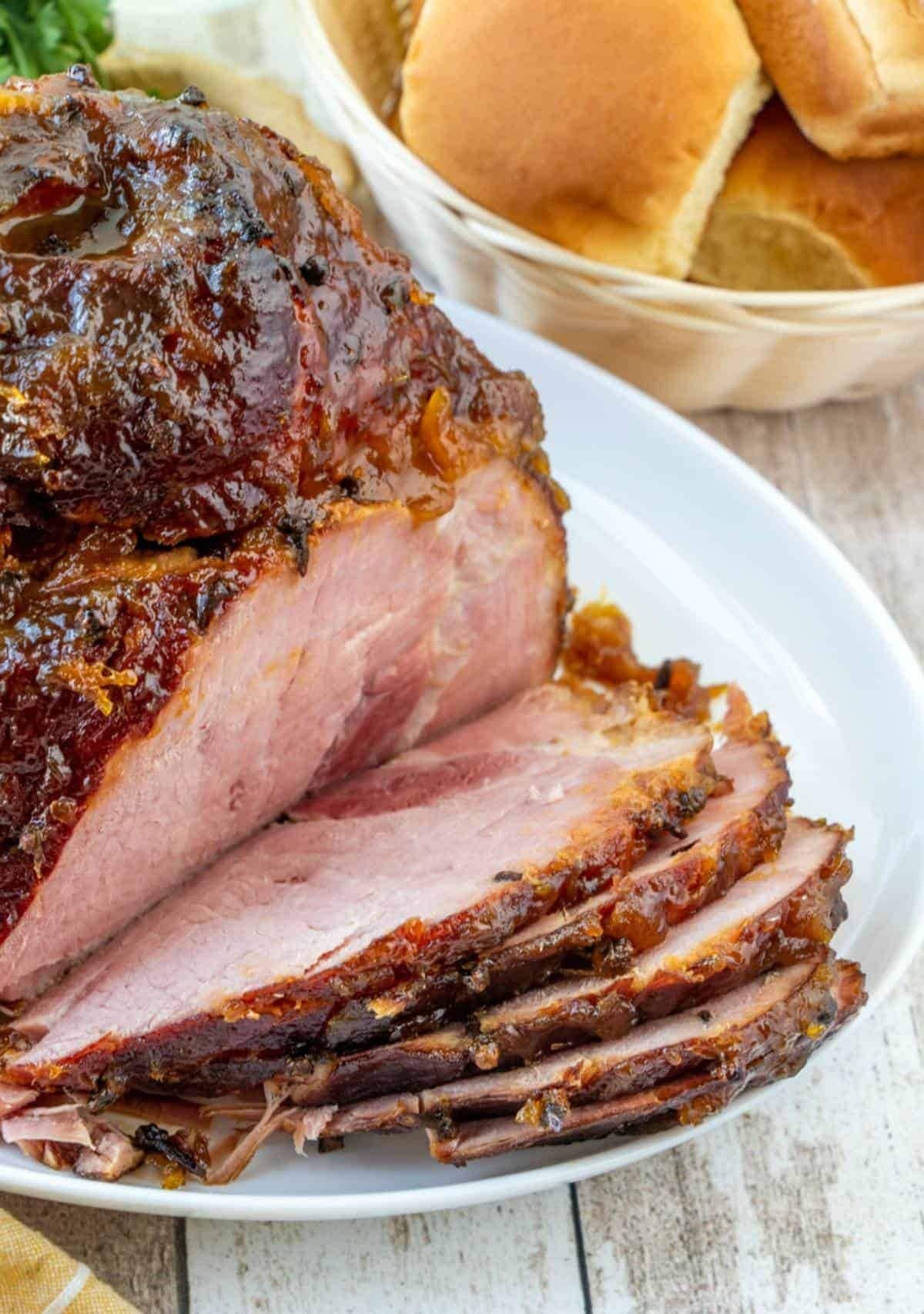Sliced whole glazed ham on a plate.