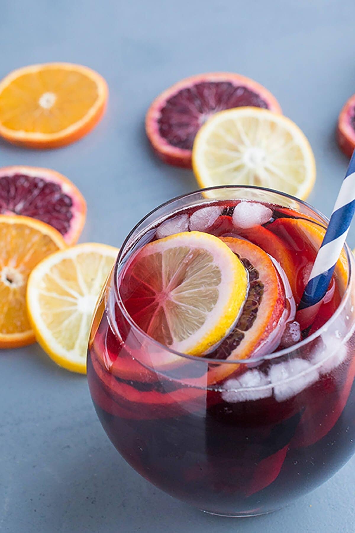 Iced red sangria on glass garnish with navel oranges and lemon slices.