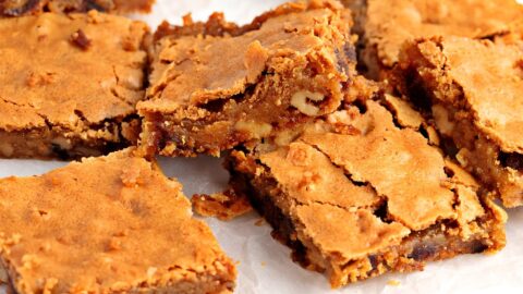 Blondie butterscotch bars on a wooden chopping board with parchment paper.