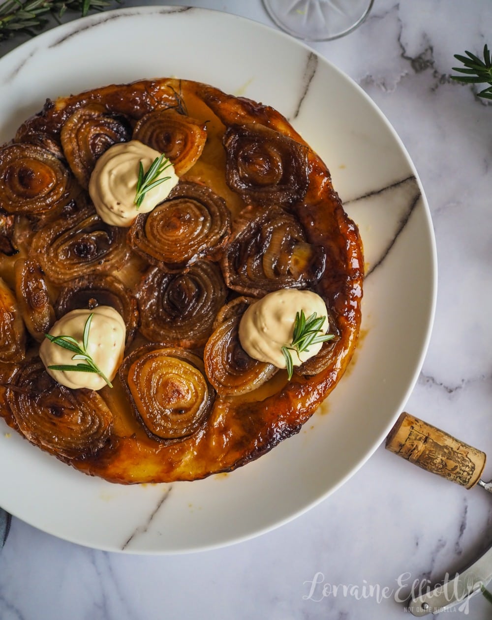 Top view of a pastry crust topped with rich, baked onions smothered in a syrupy sherry.