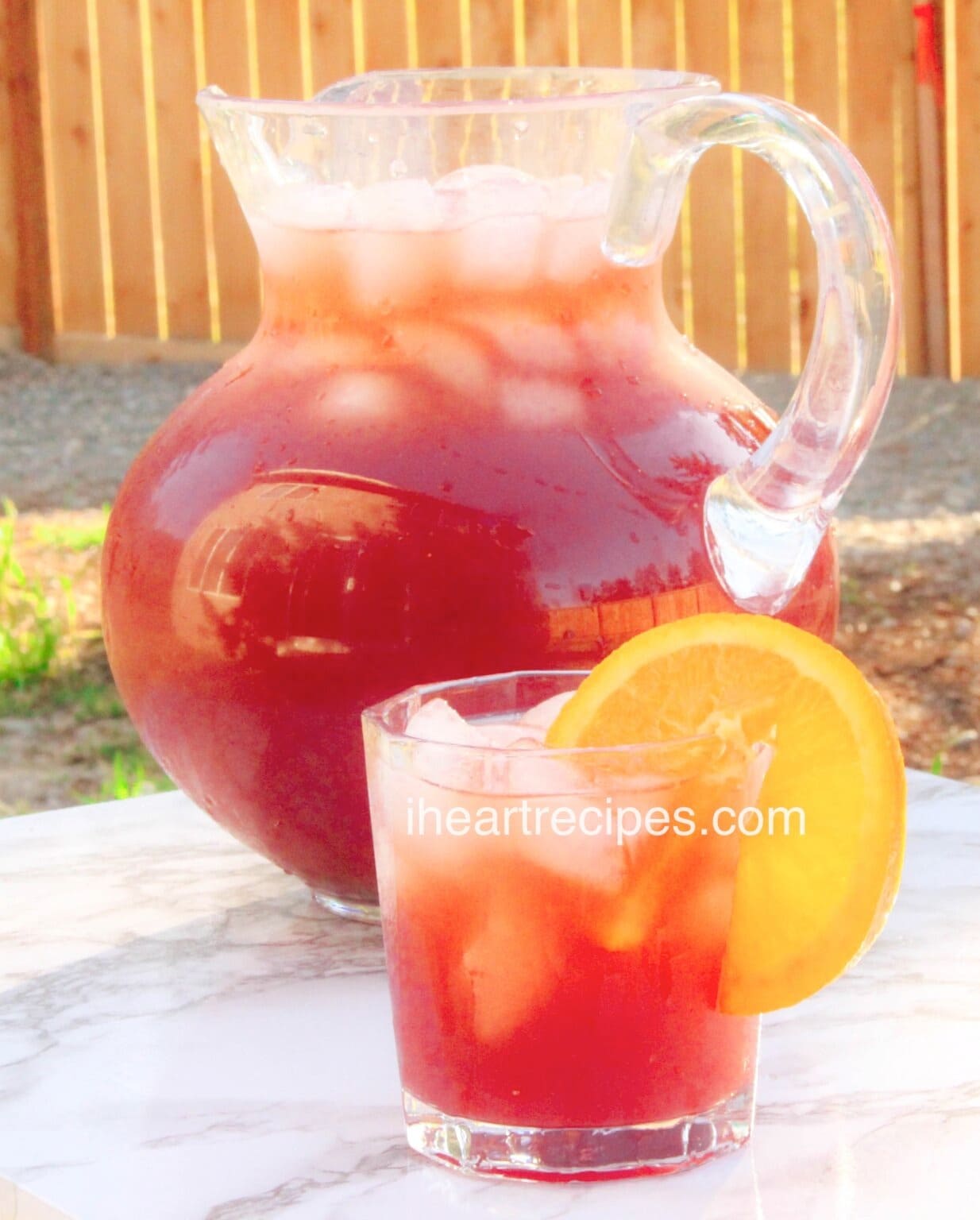 A pitcher and a glass of Fruit Punch with lemon wheel