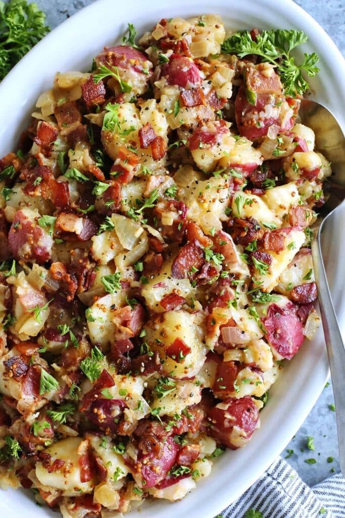 Sweet potato salad in a dish with bacon, red onions herbs and spices.