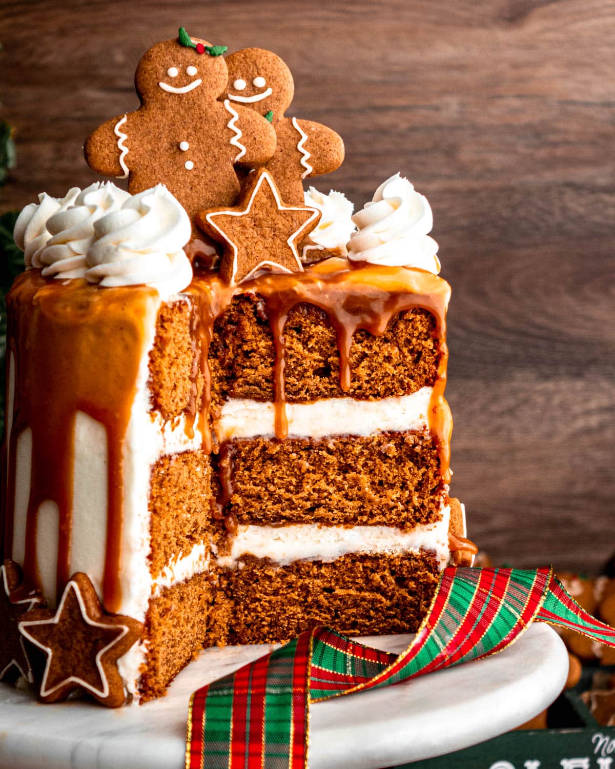 Sliced layered with cream frosting cake with gingerbread decorations on top.