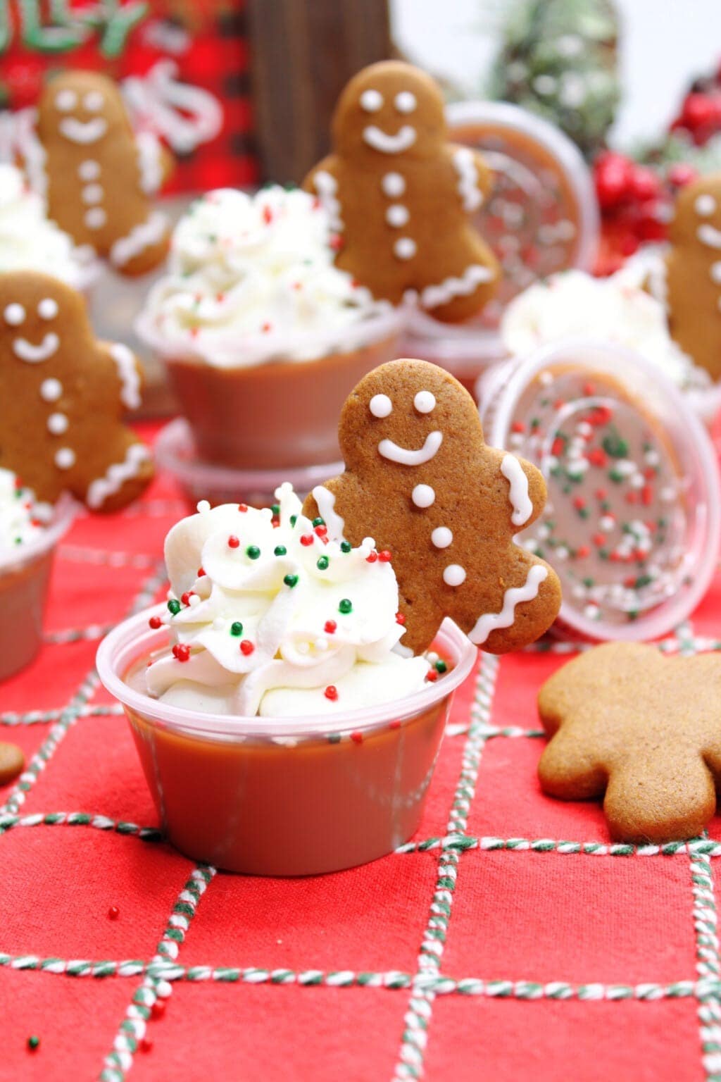 Gingerbread Jello shots on plastic cups topped with whipped cream, sprinkles and Gingerbread cookie garnish. 