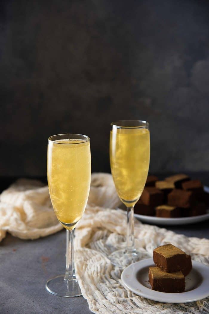 Two glasses of shimmery champagne cocktail served with chocolate bars. 