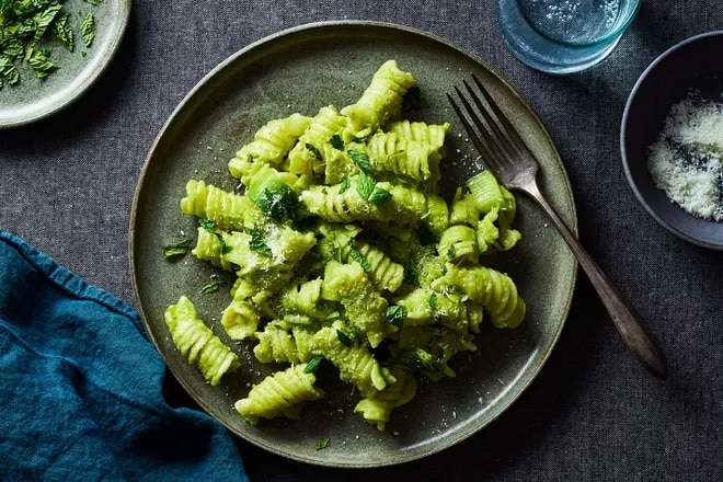 Pasta with green pea sauce & lots of pecorino served on a plate. 