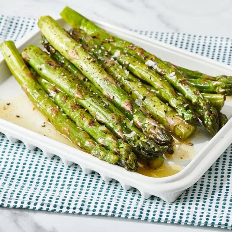 Grilled asparagus with lemon butter sauce on a plate. 