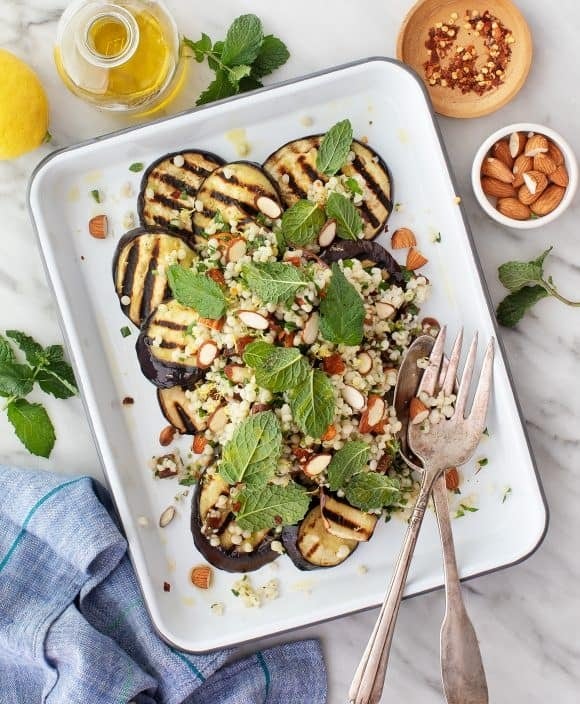Grilled eggplant topped with quinoa, nuts and mint leaves. 