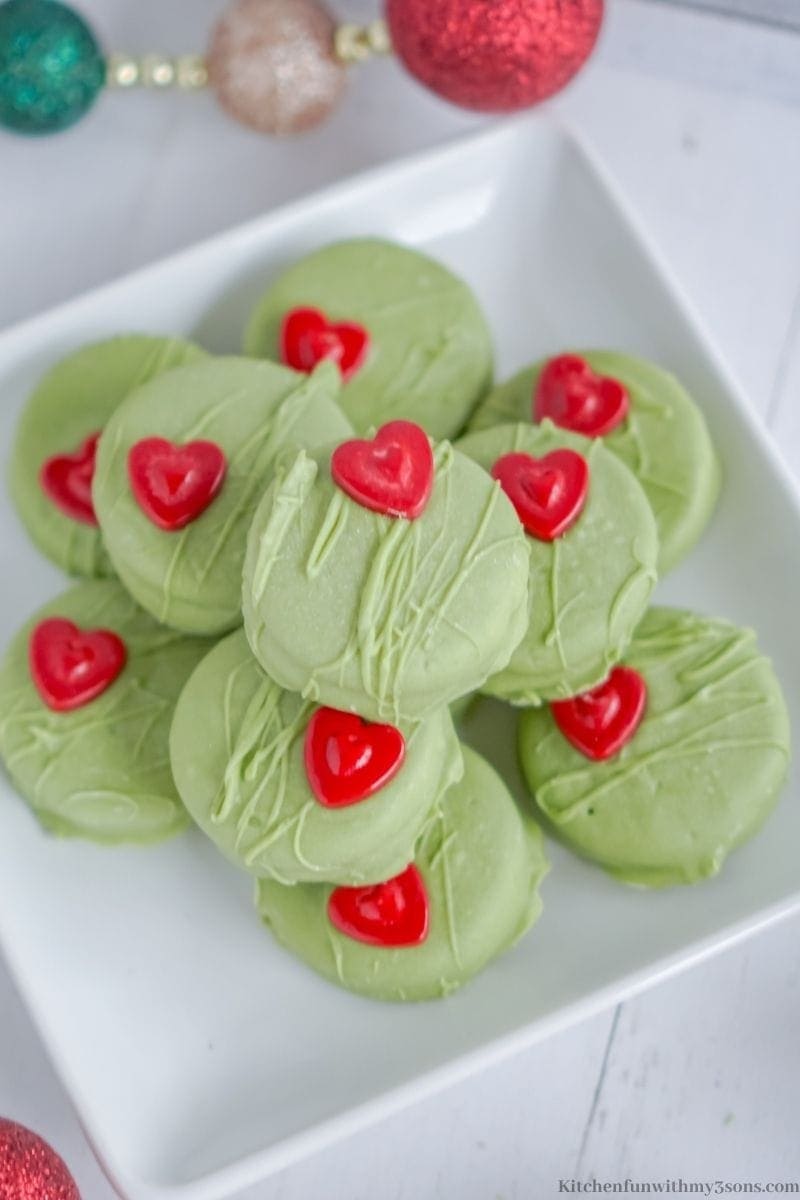 Oreos on plate coated with green colored melted chocolate with heart shaped design candies. 