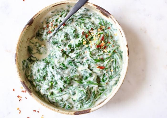 Spinach with creamy white sauce in a bowl.