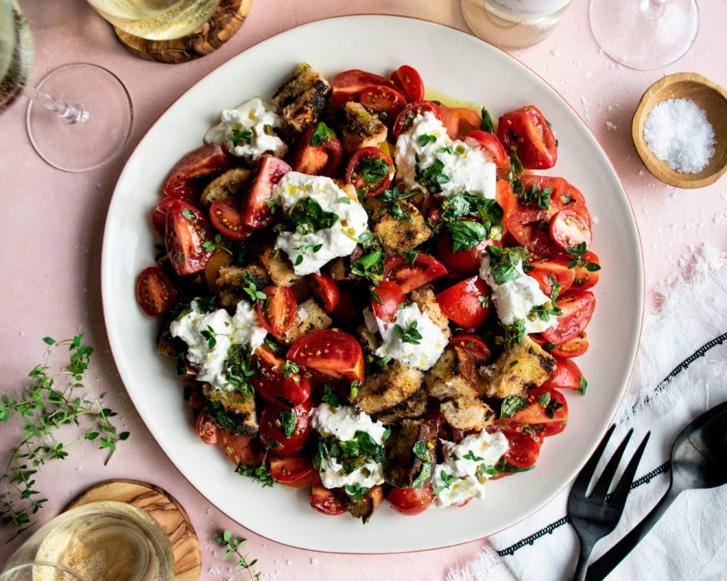 Tomato salad on plate with panzanella cheese, herbs and croutons. 