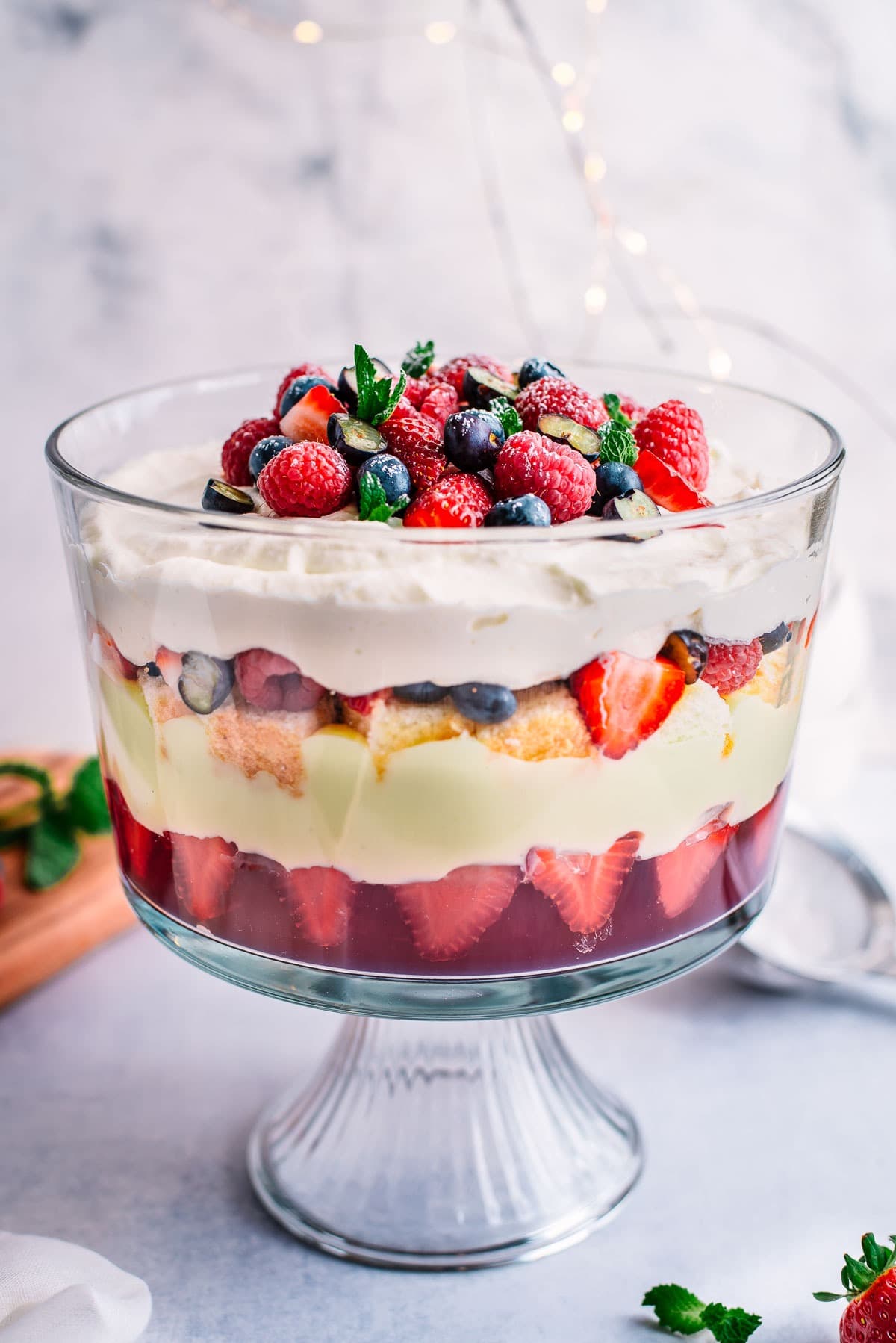 Berry trifle made with layers of fruit jelly, white chocolate custard, sponge cake, fresh berries, and mascarpone cream.