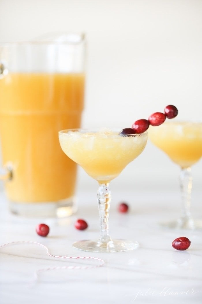 Iced pineapple cocktail in glasses garnished with grapes on stick. 