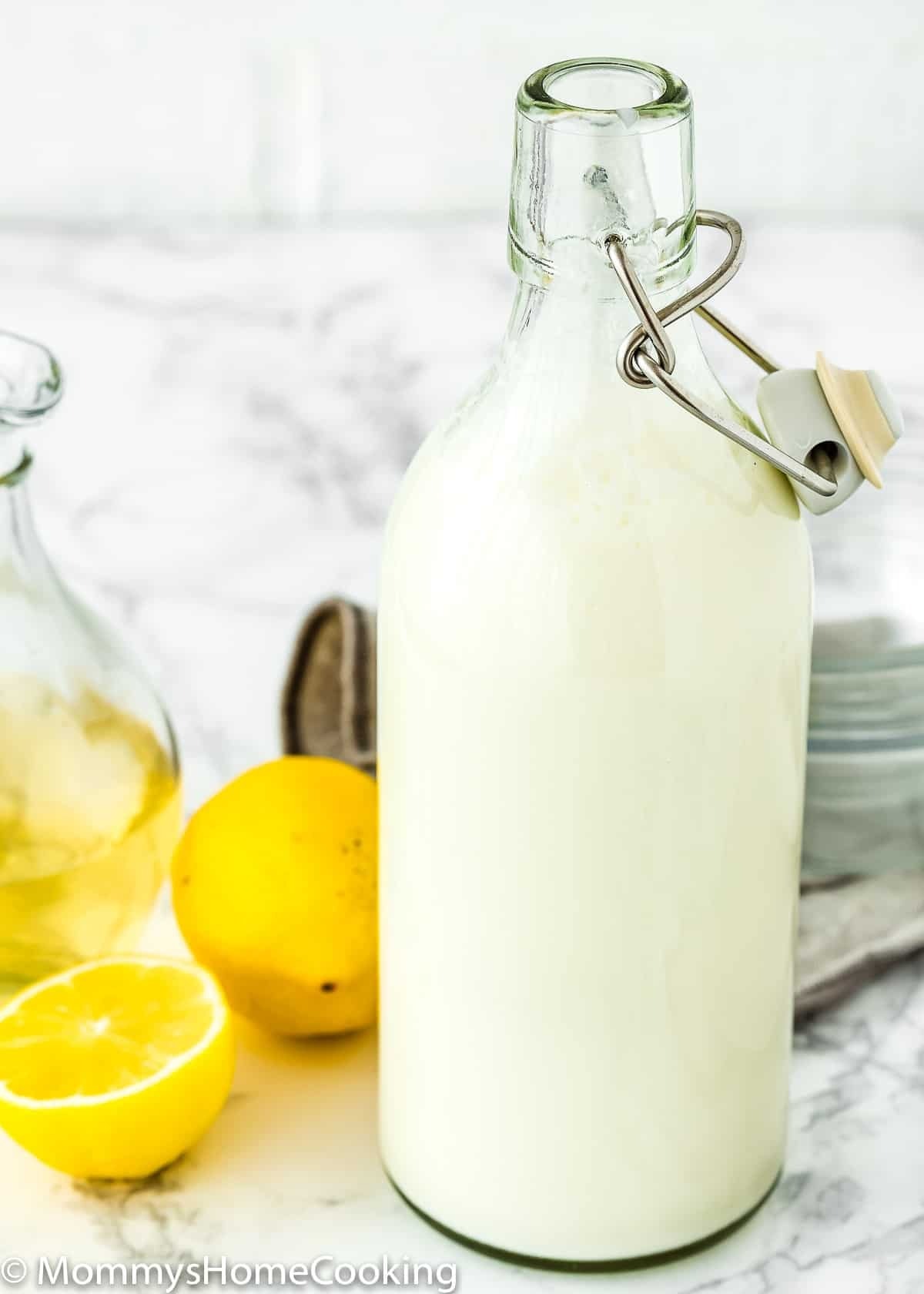 Homemade Buttermilk on a clear glass bottle with fresh lemons on marble table