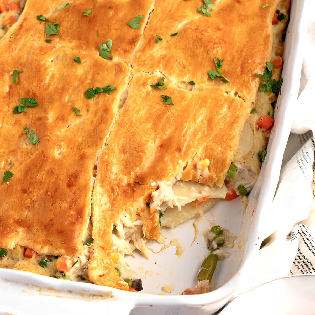 A casserole of chicken pot pie with crescent rolls, herbs, carrots, green beans and peas