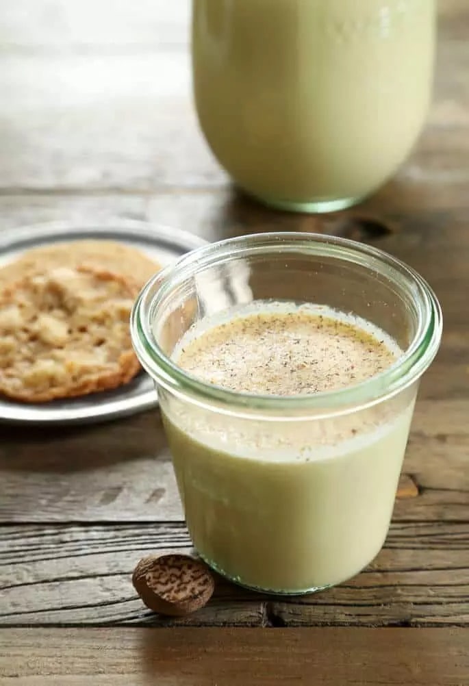Eggnog on a glass with sprinkles of spices on top.