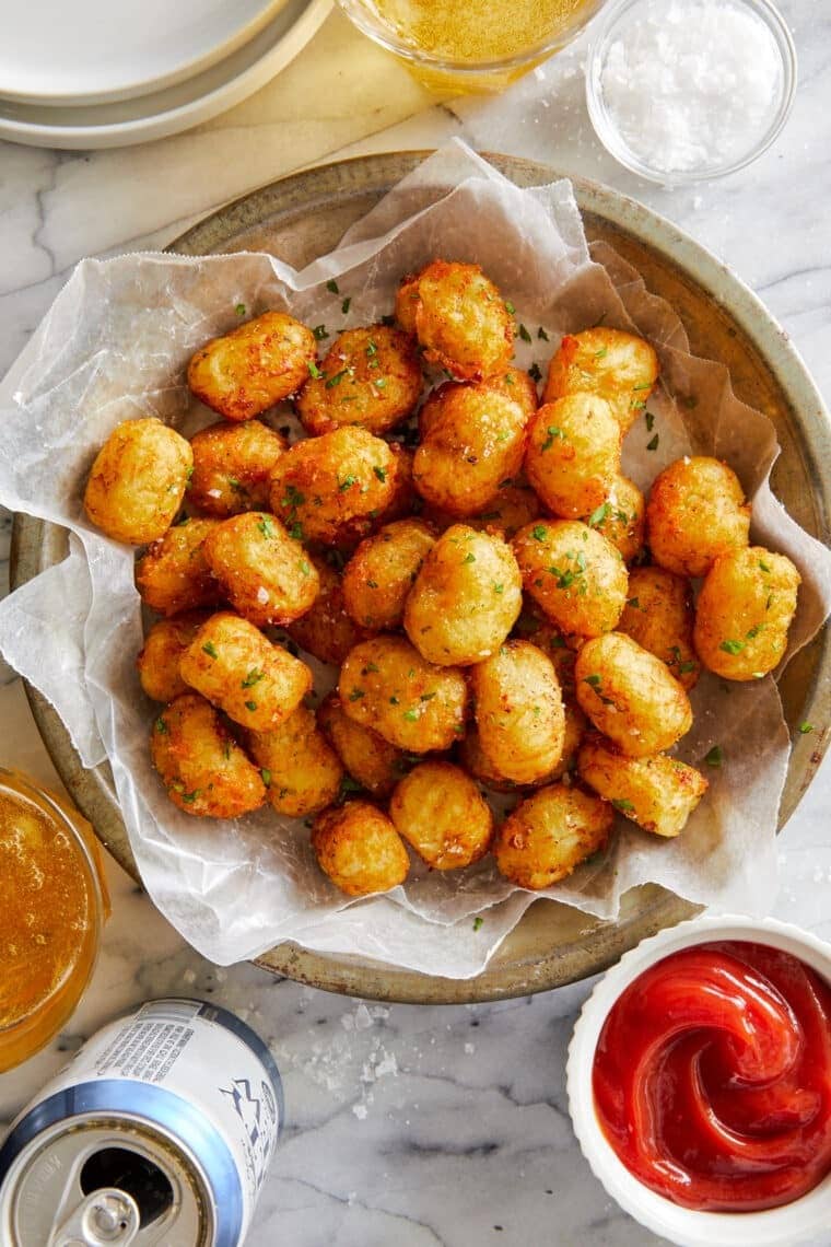 Bunch of tater tots in a bowl with parchment paper lining. 
