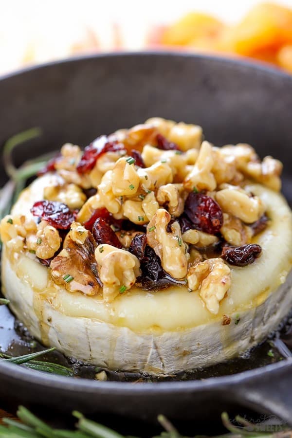 Baked brie with honey, walnuts, and cherries on a pan.