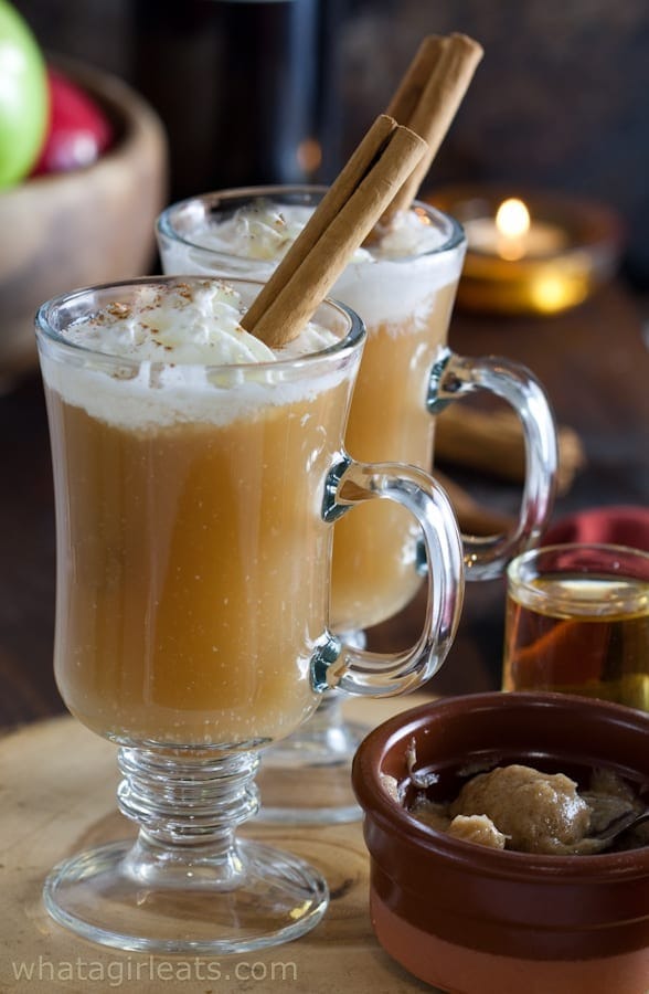 Creamy hot apple cider drink topped with whipped cream and cinnamon sticks. 