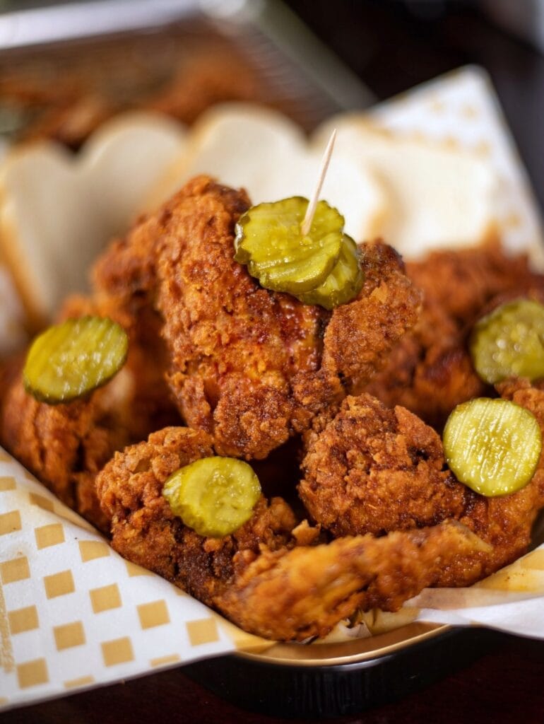 Breaded chicken wings garnished with slices of pickles on toothpick. 